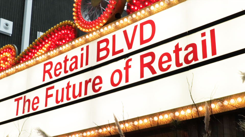 An illuminated advertisement in red letters reading "Retail BLVD – The Future of Retail".