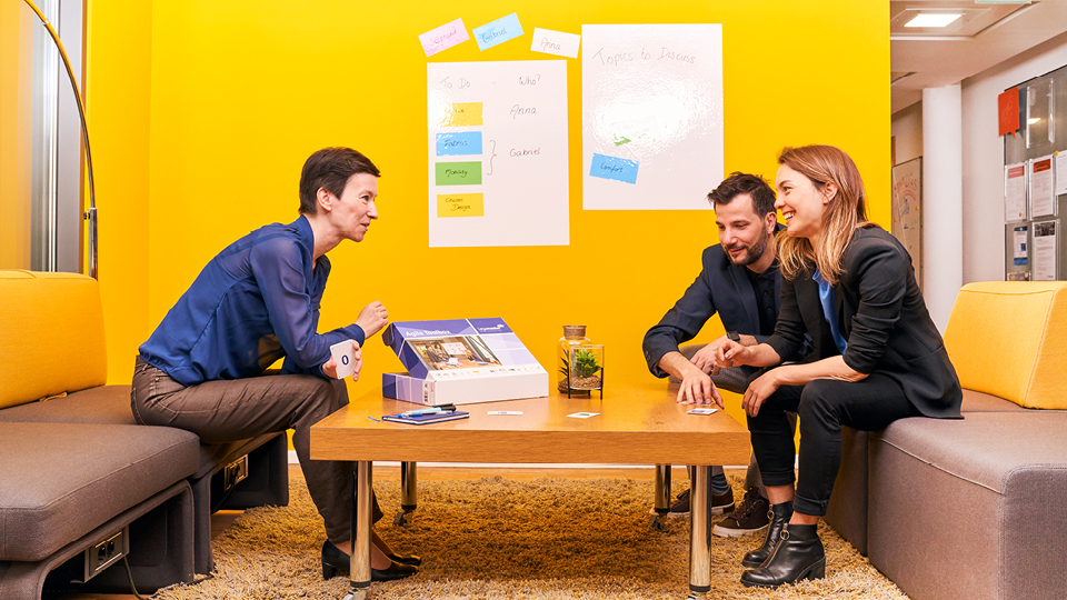 Eine Teambesprechung in einem gelb gestrichenen, modernen Büroraum