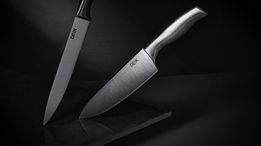 Deik-branded kitchen knives stand upright in a moody setting.