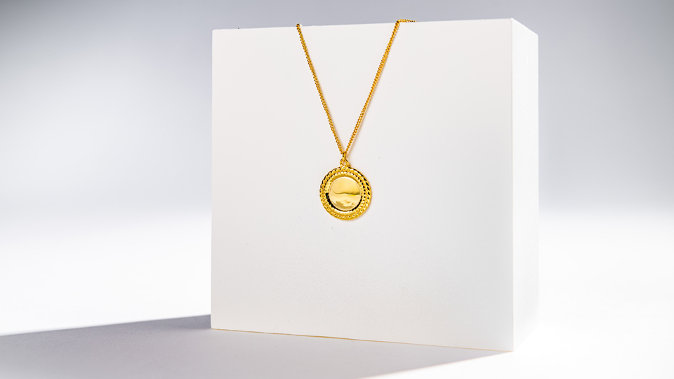 A gold necklace draped on a white box