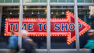 Schaufenster mit LED-beleuchtetem Pfeil und dem Slogan "Time to shop"