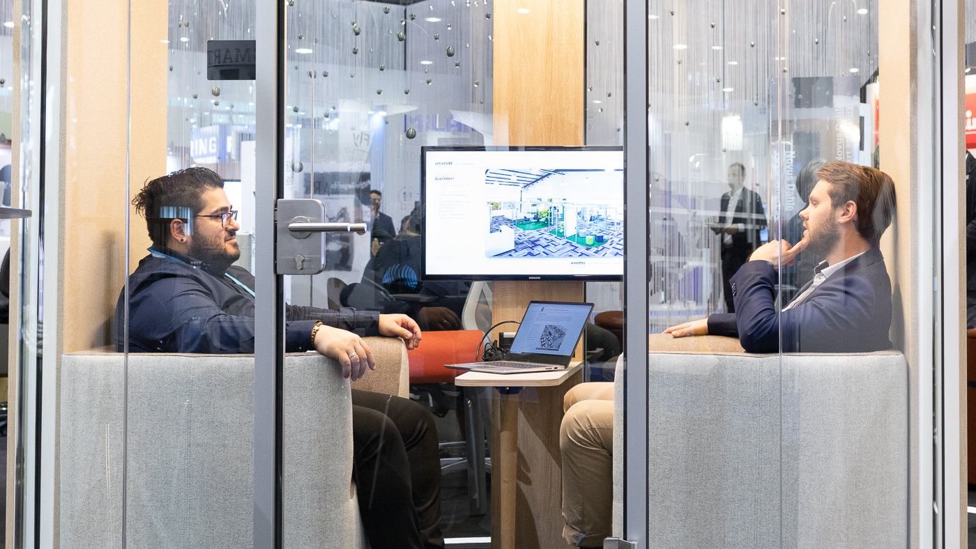 2 men sitting in a conference booth and talking