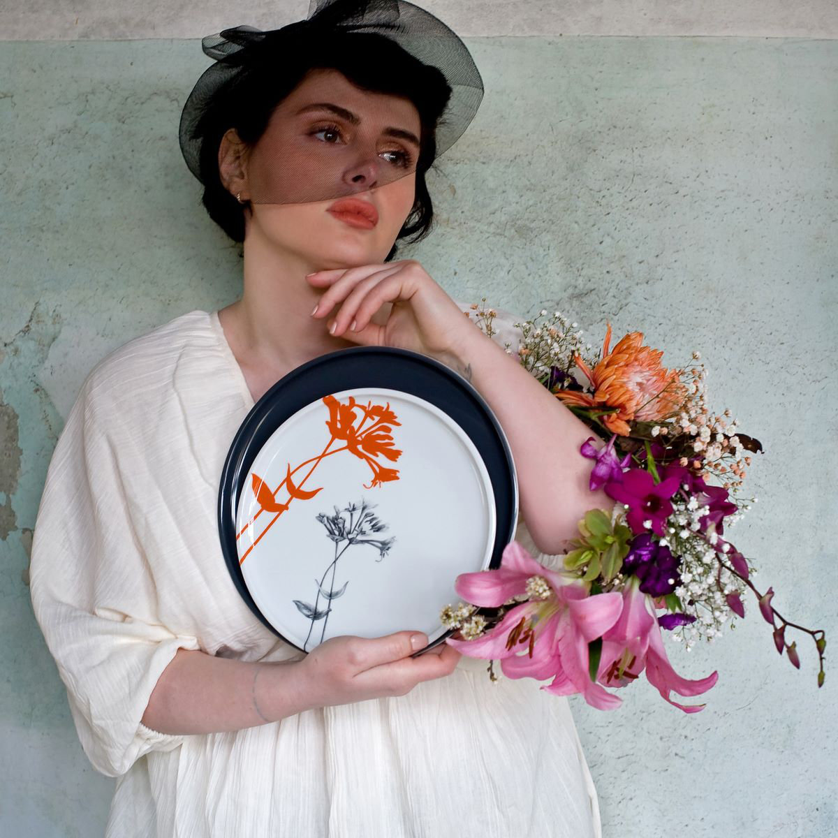 Frau mit einem Teller von Mittelpunkt sowie Blumen in der Hand