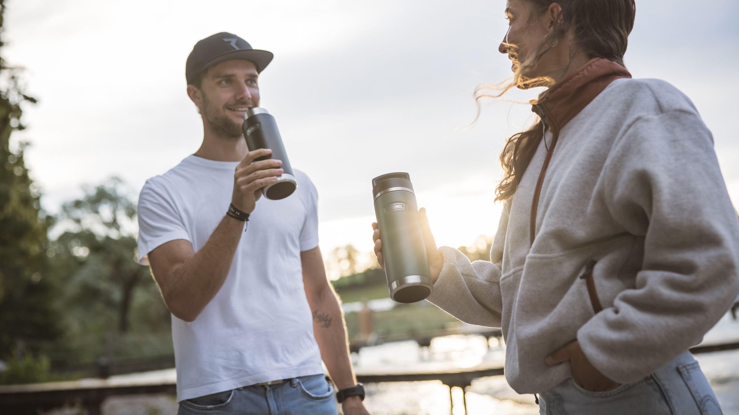 young man and woman with thermos bottles in their hands