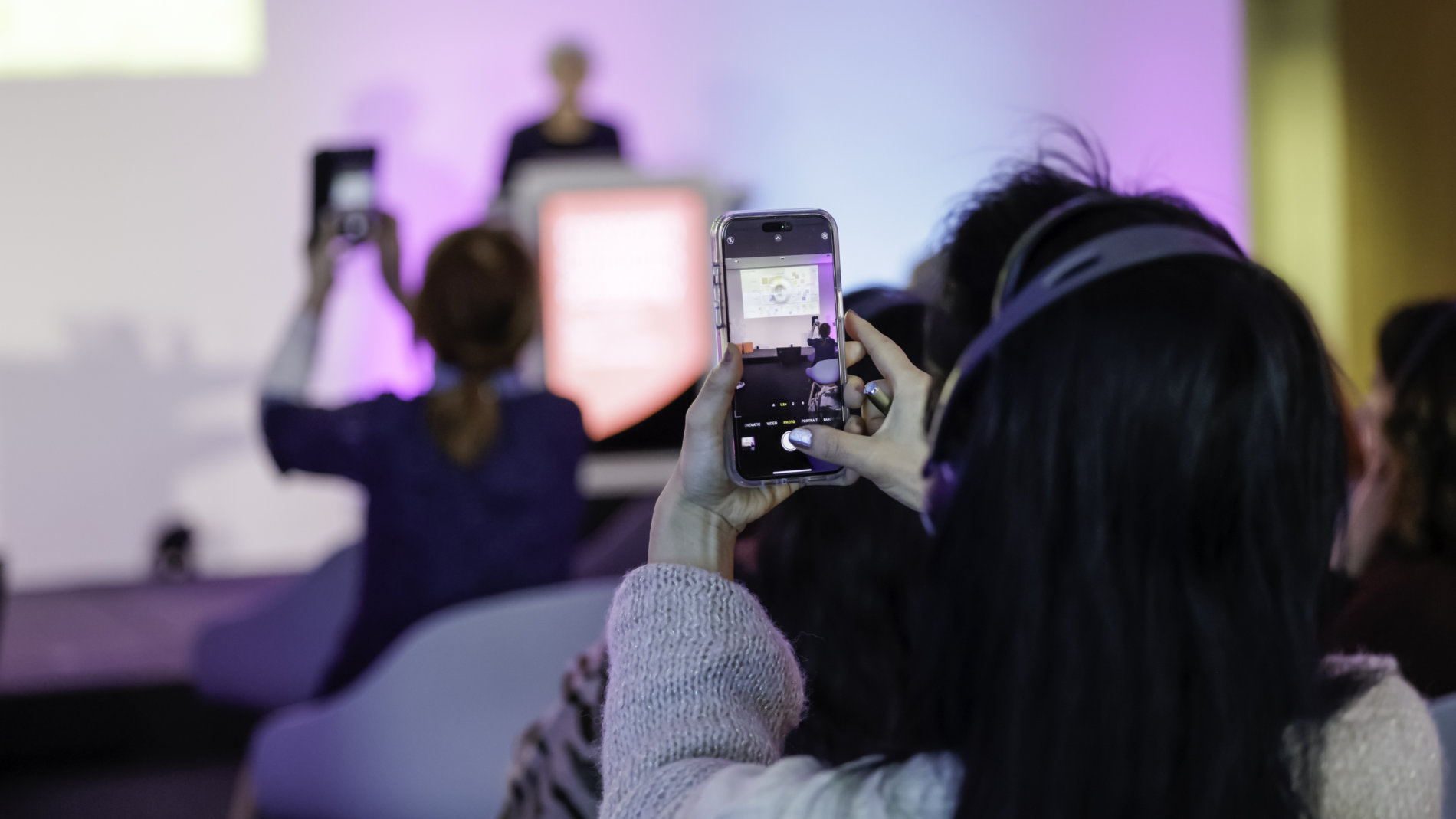 Visitors to a lecture take photos with their smartphones