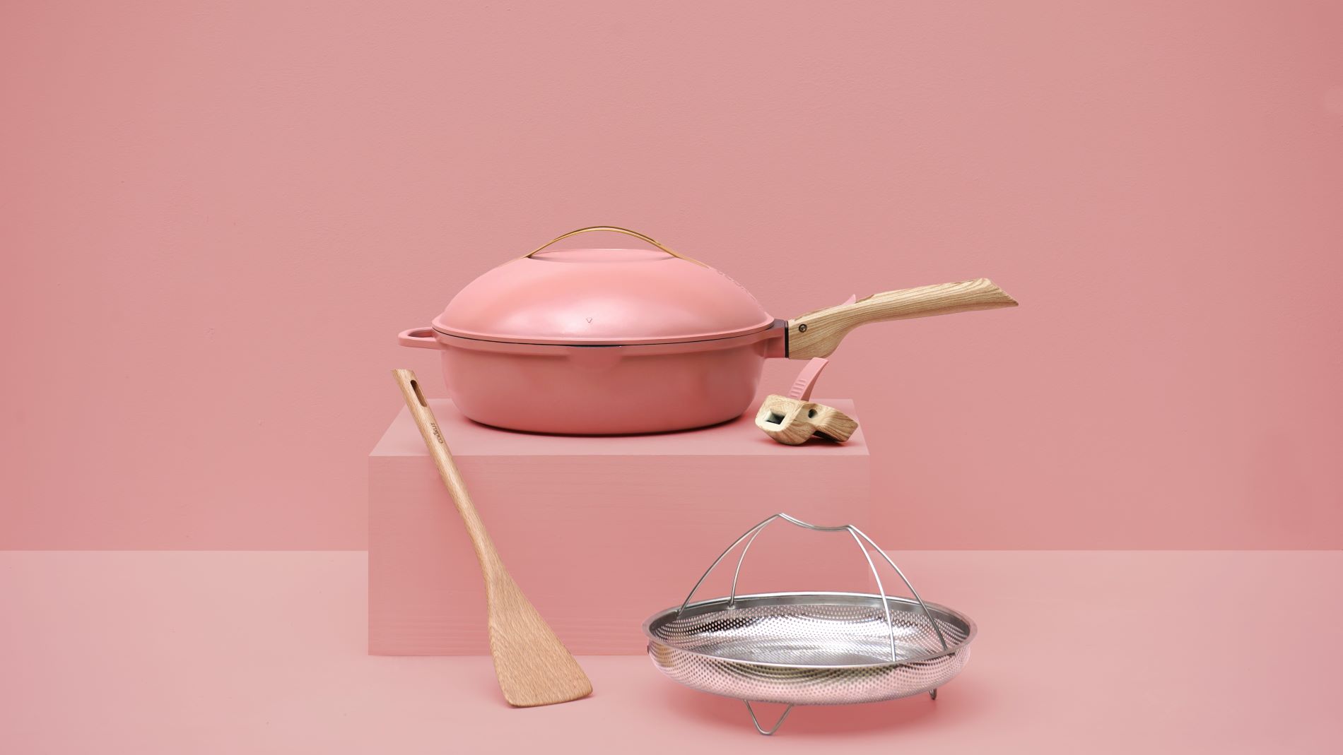 Pastellfarbener Bräter mit Holzgriff und Küchenzubehör