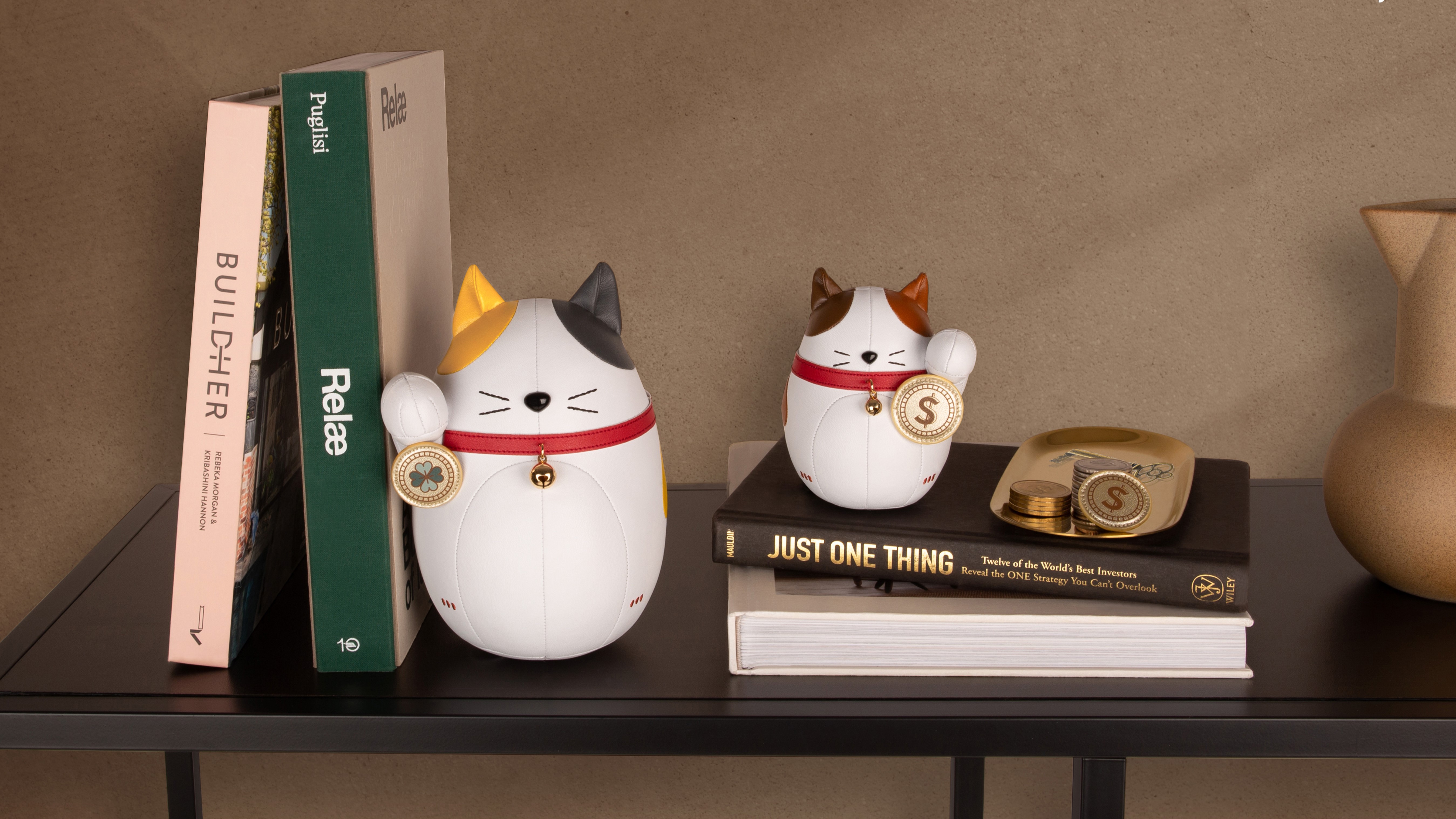 Dekorative Katzenfiguren auf Bücherregal mit Vasen